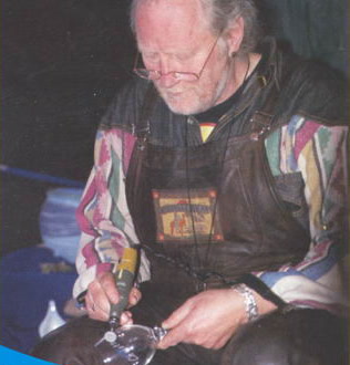 Peter Eicke beugt sich über ein Glas und graviert es mit dem Handstück